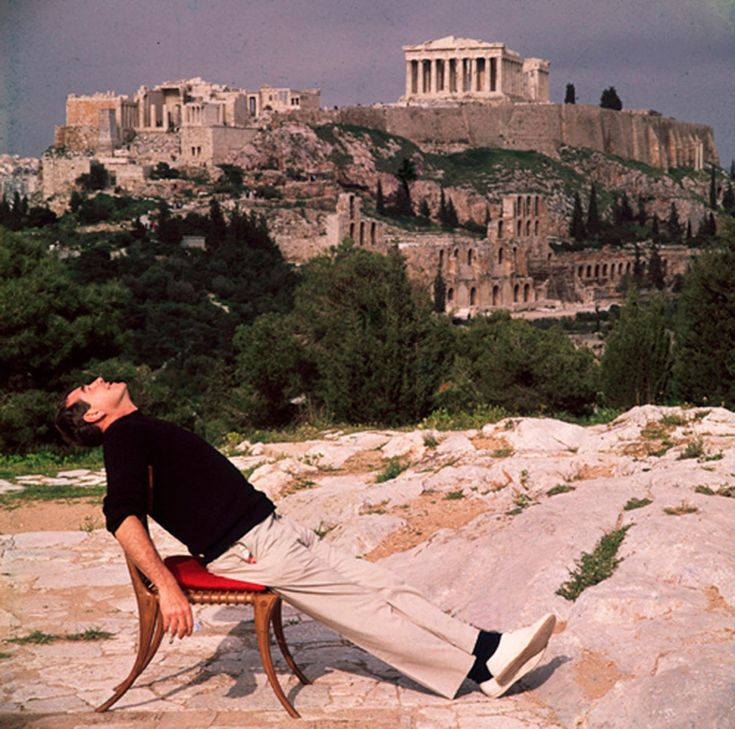 Man tillbakalutad på stol framför Akropolis